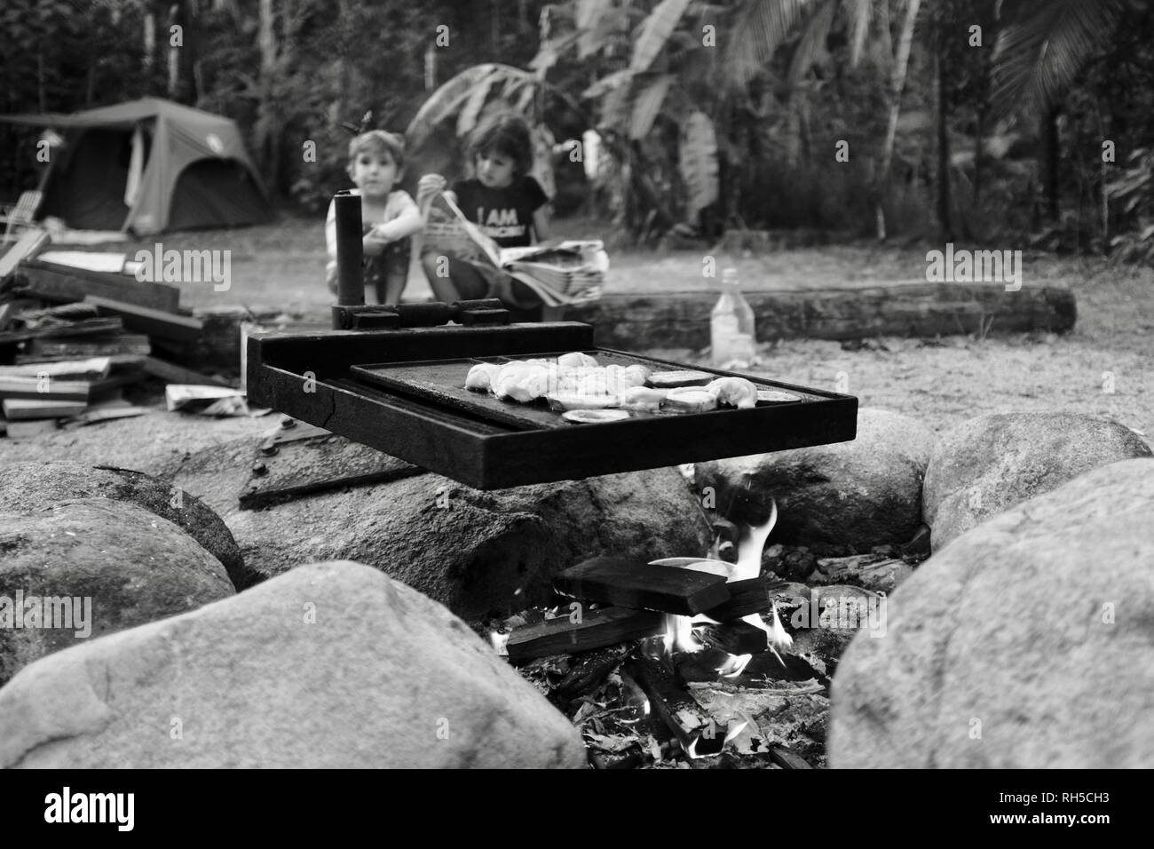 An australian style bush bbq with food cooking over a campfire with two
