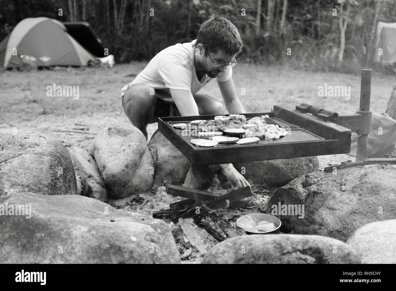 A young man cooking on an australian style bush bbq hires stock