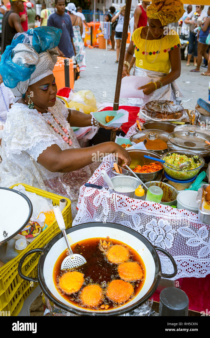 SALVADOR, BRAZIL - FEBRUARY 2, 2016: Women in traditional Baiana dresses fry Brazilian acaraje fritters in the thick brown oil of the dende palm fruit Stock Photo