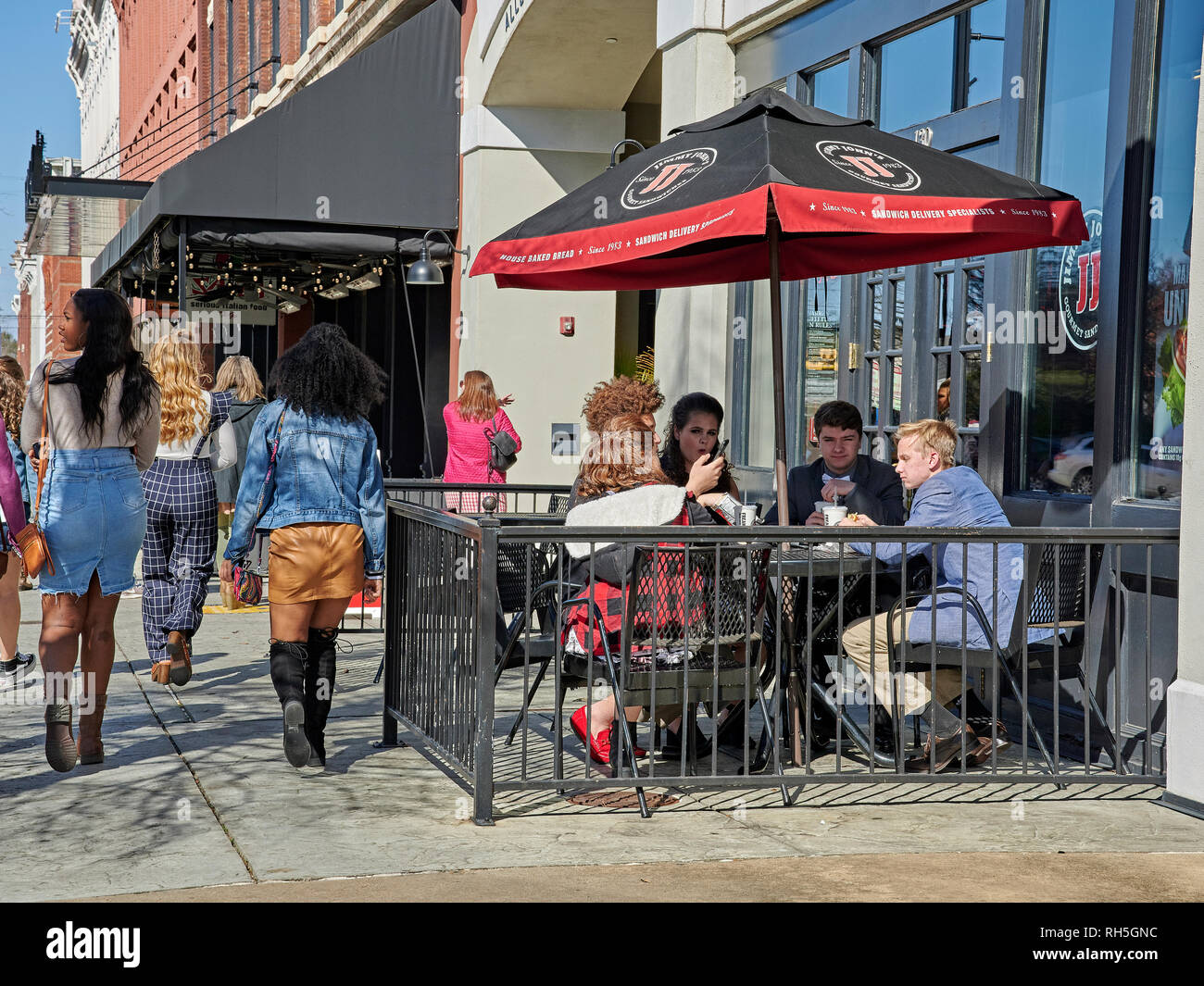 Group of teens or teenagers eating at a sidewalk cafe, Jimmy Johns restaurant or sandwich shop in Montgomery Alabama, USA. Stock Photo