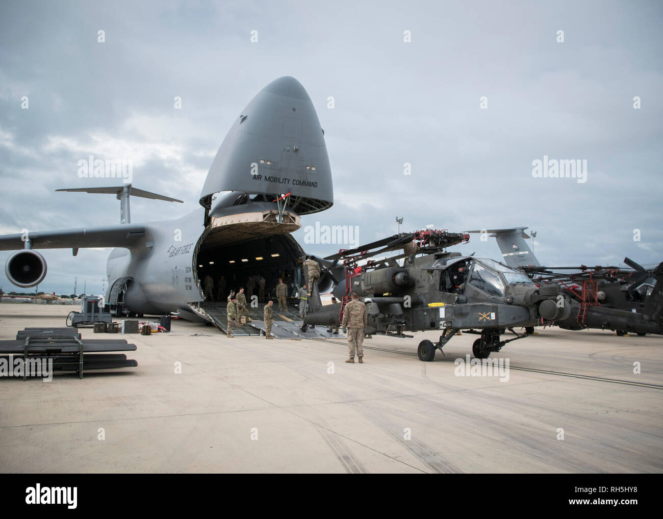 190130-N-TR141-0034 NAVAL STATION ROTA, Spain (January 30, 2019) Soldiers assigned to the 1st Armored Division and 1109th Theater Aviation Sustainment Maintenance Group load an AH-60 Apache helicopter onto a C-5 aircraft during Intermodal operations. Intermodal operations combine sea and air transportation to reduce cargo handling, improve security, minimize damage and allow quicker transportation. (U.S. Navy photo by Mass Communication Specialist 1st Class Benjamin A. Lewis) Stock Photo