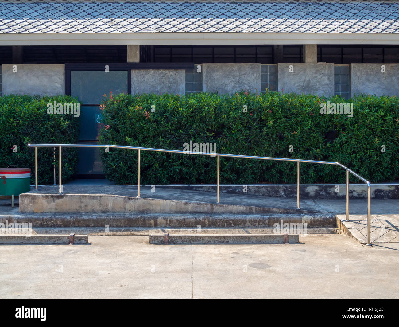 Old grunge wheelchair ramp with metal bar near empty car parking in ...