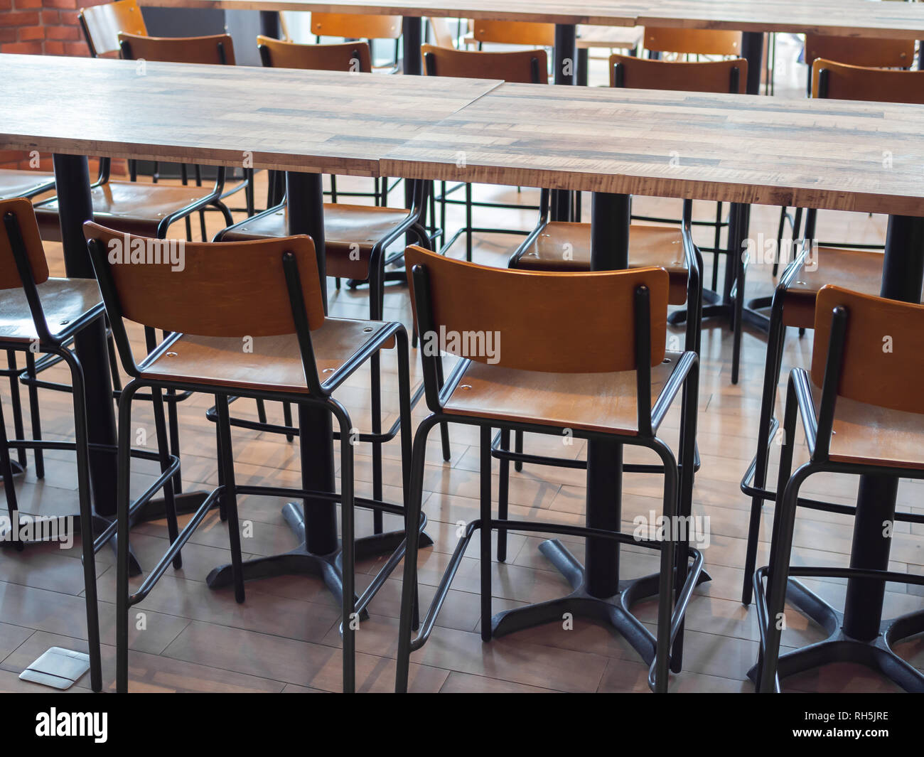 Row of retro style wooden bar stools and modern wooden tables in cafe