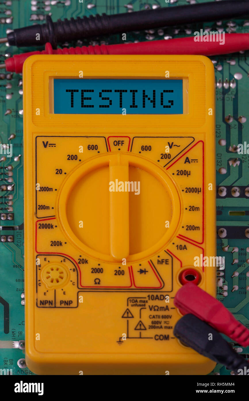 Digital multimeter multitester on a circuit board with the word testing
