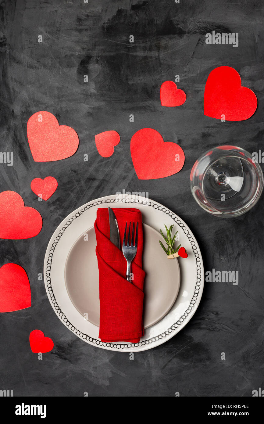 Holiday and romantic serving plate with fork, knife, napkin, strawberry and red heart shaped cards at black background. Top view, close up Stock Photo