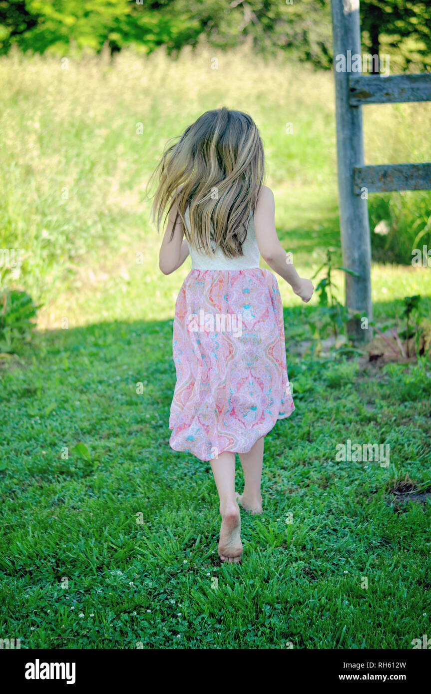 girl with long blonde hair in a dress running Stock Photo