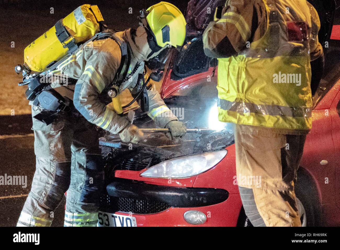 A member of the Fire Service is seen in full respiratory system with a Halligan Bar to remove the car's battery. A car caught fire tonight on the B9096 in Tullibody. Fire & Rescue and Police were on scene. There were no injuries. Fire & Rescue brought the fire under control and put it out. Stock Photo