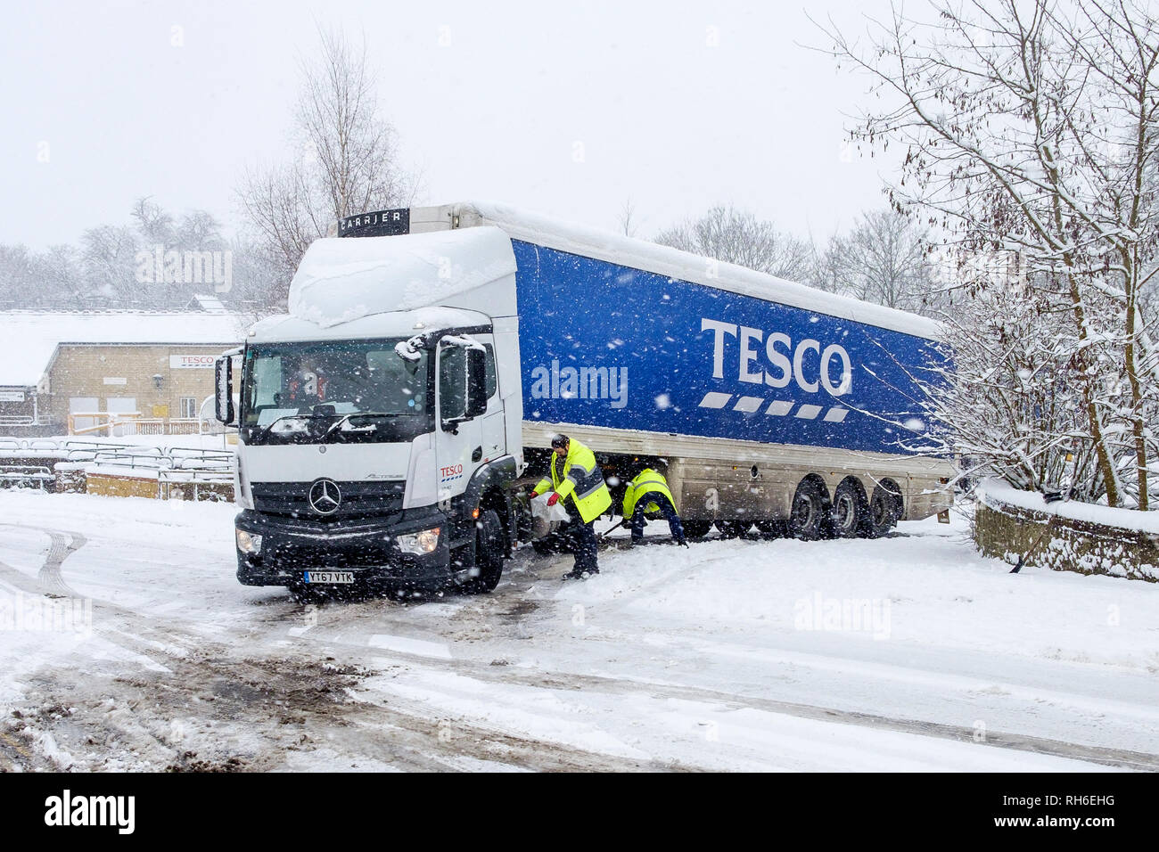 Chippenham, Wiltshire, UK. 1st February, 2019. Tesco's staff are pictured as they try to free a Tesco delivery truck that has become stuck in the snow as it tries to leave the store car park in Chippenham town centre. Credit: Lynchpics/Alamy Live News Stock Photo