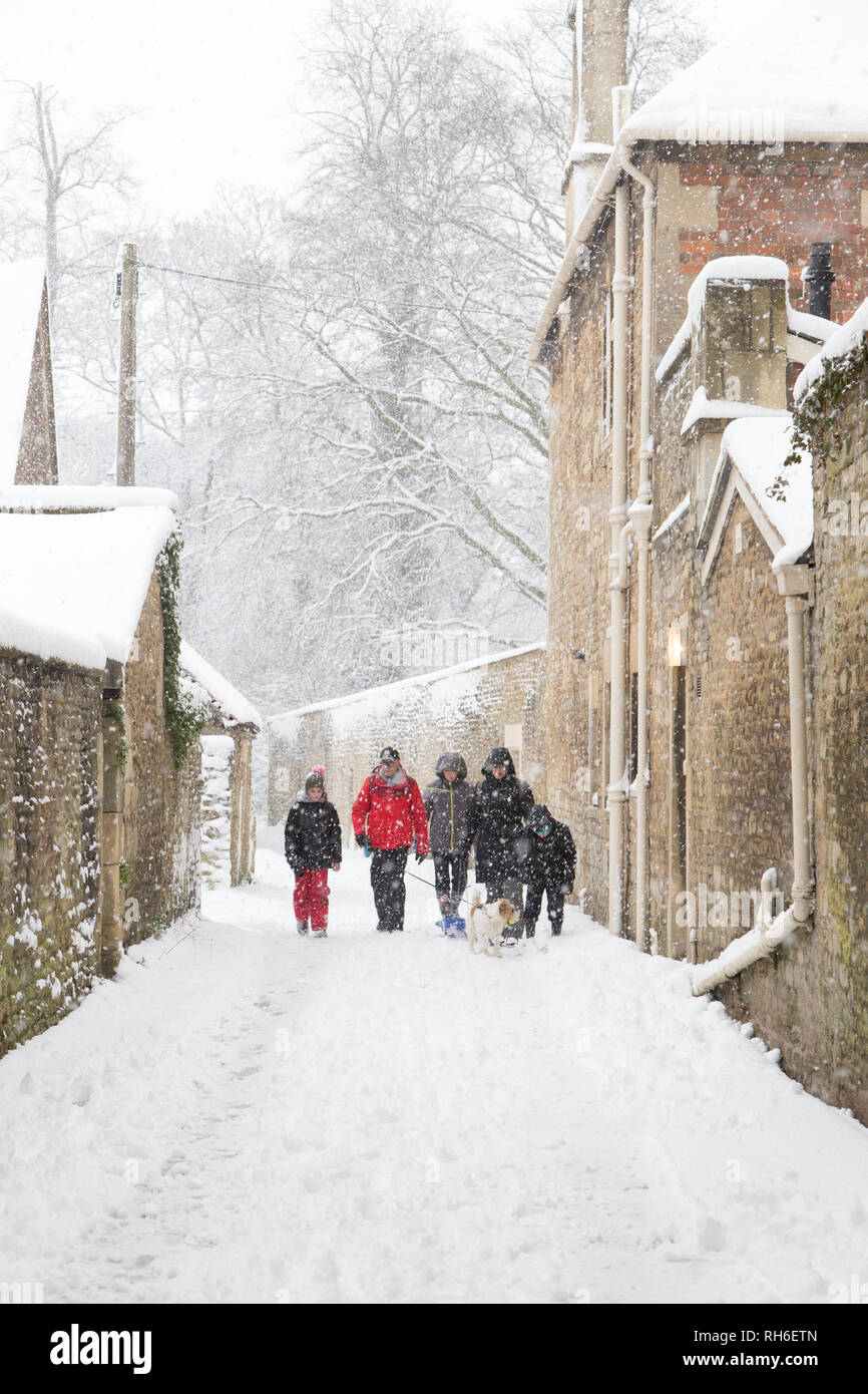 Corsham, Wiltshire, UK. 1st February, 2019. Heavy snowfall blankets the ancient town centre, home to the TV series Poldark and now a wintery scene which was forecast, though arrived late and much heavier than earlier predictions. Local residents brave the cold conditions as heavy snowfall continues to accumulate   throughout the day - with revised forecasts reporting sustained snow until 6pm this evening. The roads   are empty of cars, many schools and business remain closed whilst the wintery weather continues it's icy   grip in Wiltshire. Credit: Wayne Farrell/Alamy Live News Stock Photo