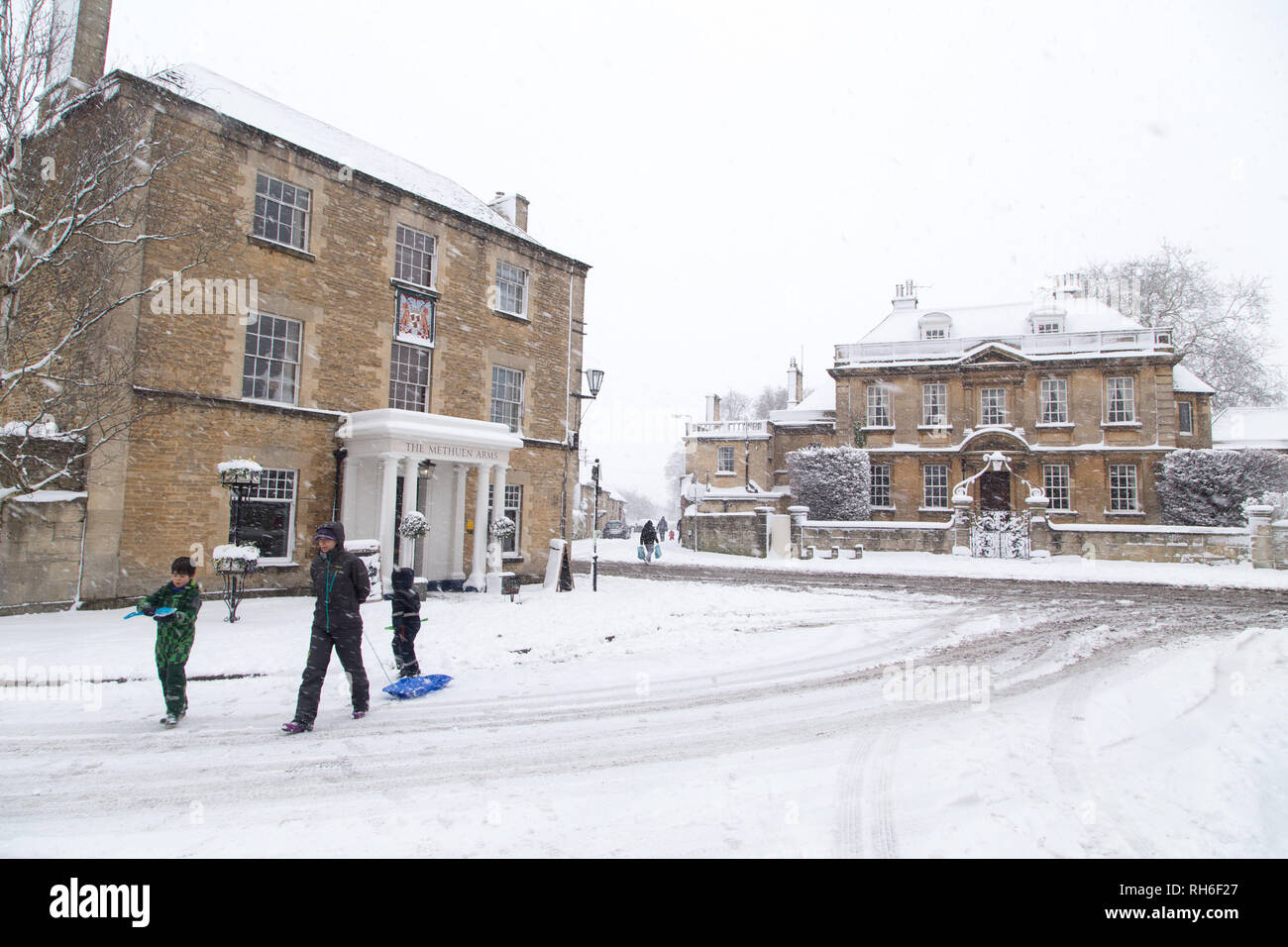 Corsham, Wiltshire, UK. 1st February, 2019. Heavy snowfall blankets the ancient town centre, home to the TV series Poldark and now a wintery scene which was forecast, though arrived late and much heavier than earlier predictions. Local residents brave the cold conditions as heavy snowfall continues to accumulate   throughout the day - with revised forecasts reporting sustained snow until 6pm this evening. The roads   are empty of cars, many schools and business remain closed whilst the wintery weather continues it's icy   grip in Wiltshire. Credit: Wayne Farrell/Alamy Live News Stock Photo