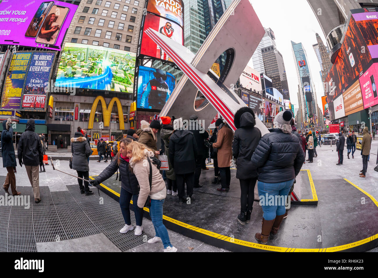 New York, USA. 1st Feb 2019. Tourists and the media crowd 'X', the winner of the Times Square Valentine Heart Design in Times Square in New York, at its unveiling on Friday, February 1, 2019. The sculpture, designed by Reddymade, uses two intersecting aluminum planes with a cylinder shape cut at the intersection that viewed from below forms a heart shape. Additionally, the X symbol has represented kisses and expressions of love since the 19th century. 'X' will on view through February.  (© Richard B. Levine) Credit: Richard Levine/Alamy Live News Stock Photo