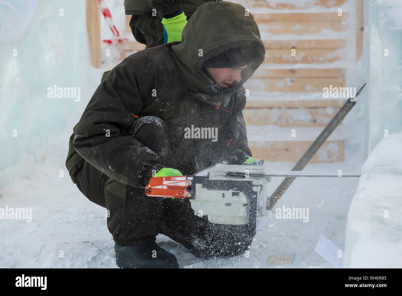 Work installer with a chainsaw in his hands undercut ice block Stock