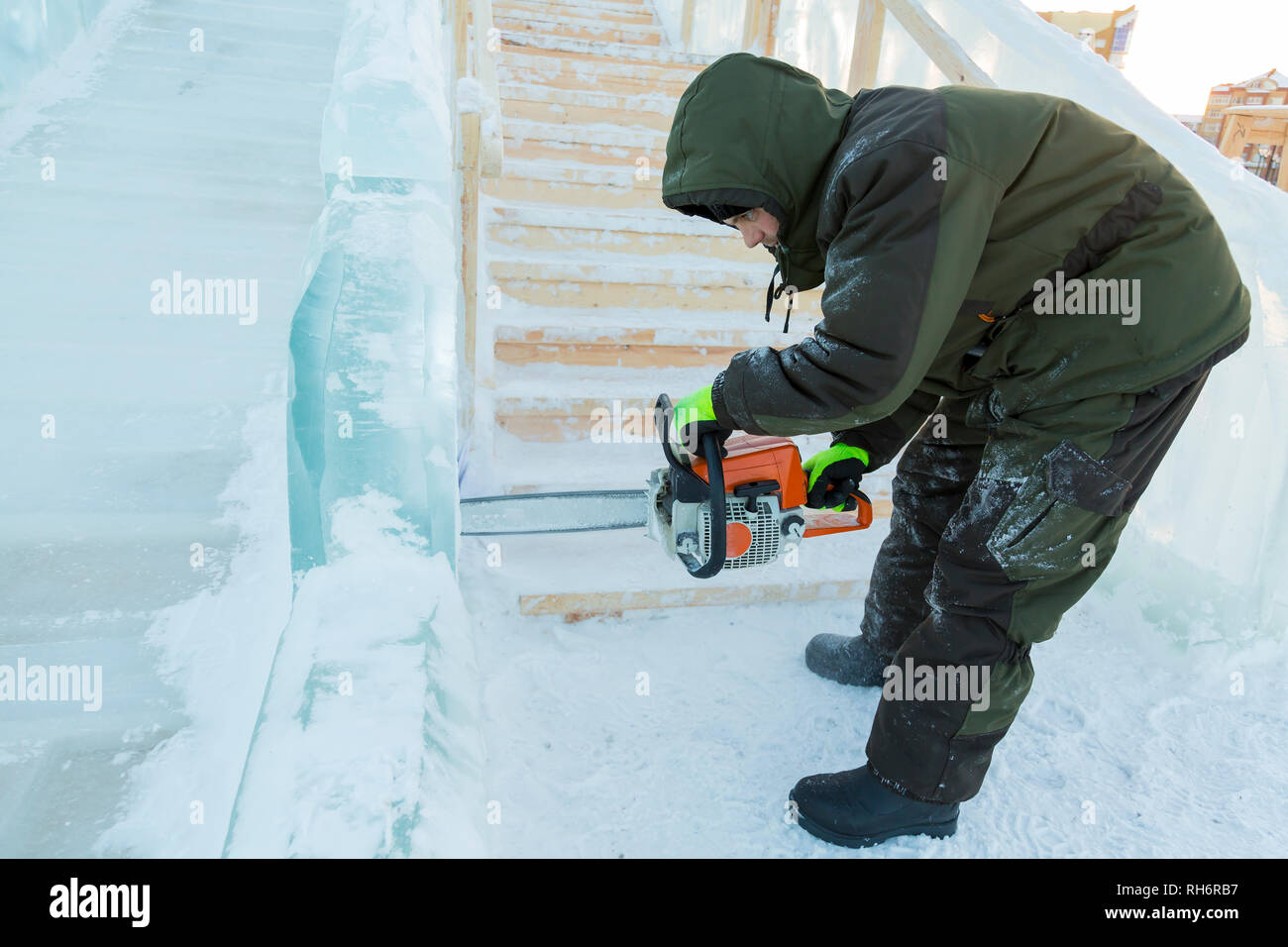 Work installer with a chainsaw in his hands undercut ice block Stock