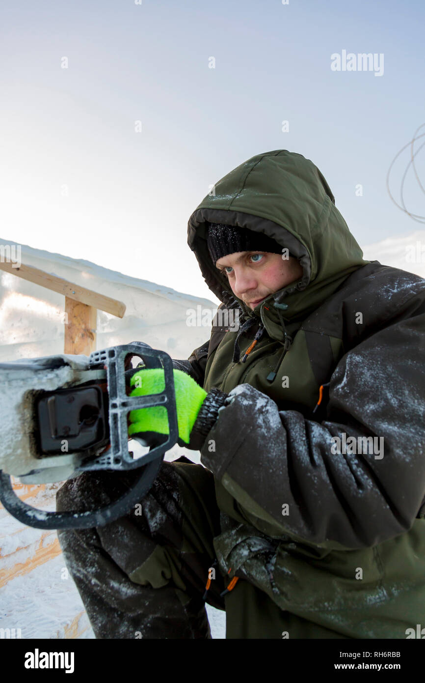 Work installer with a chainsaw in his hands undercut ice block Stock