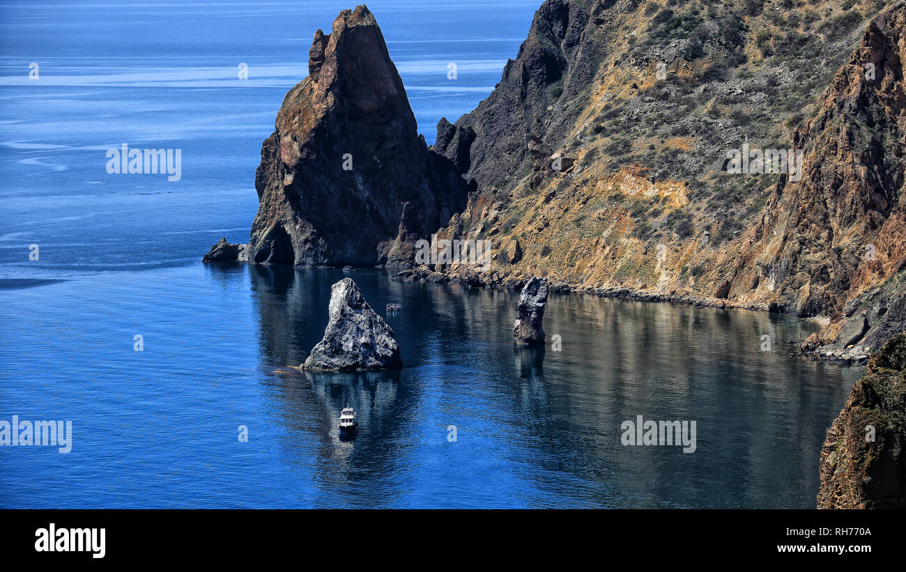 seascape mountains and rocks a lonely ship on the water summer season Stock Photo