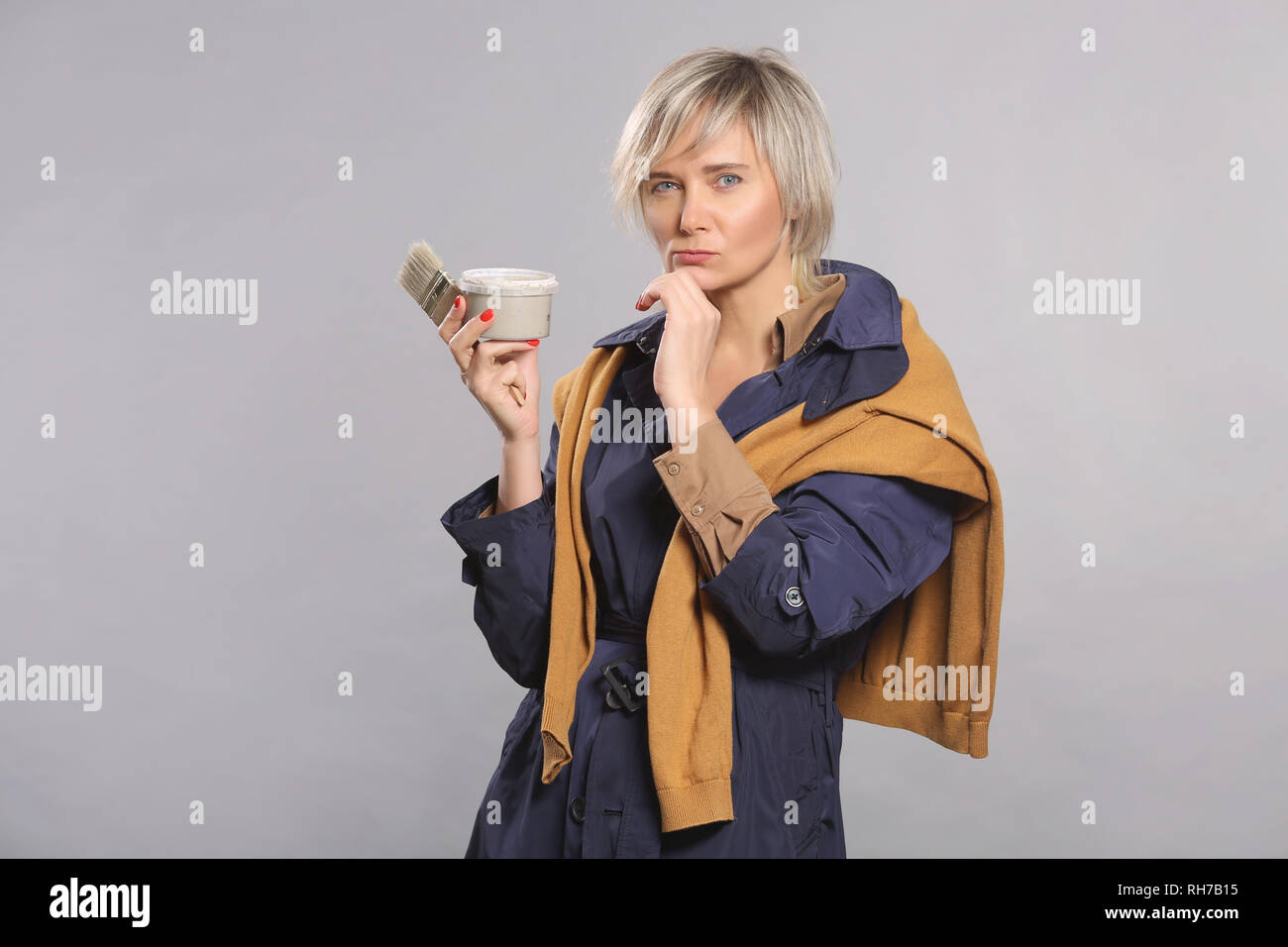 woman Painter, an artist, in a sweater and robe, holding a brush and gray paint, he thinks to paint, 40th, on isolated background Stock Photo