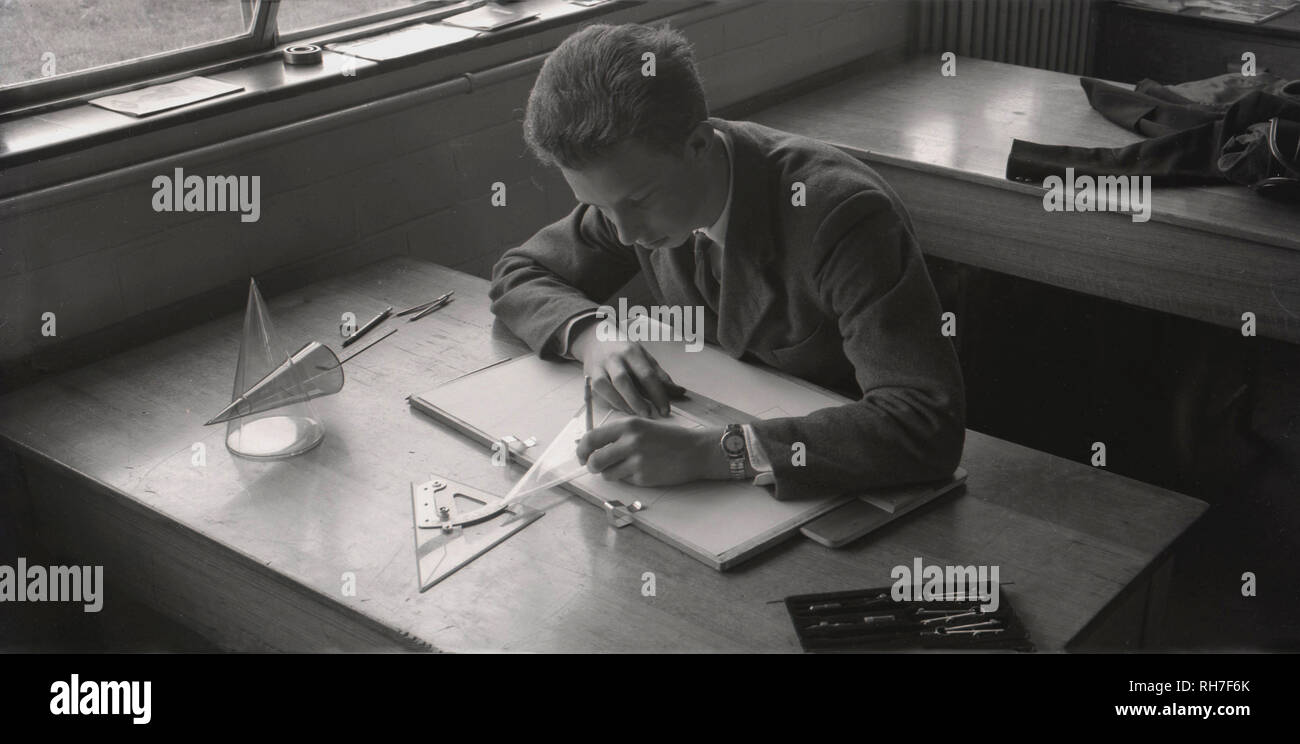 1950s, a young male student sitting at a desk with manual tools, pen, protractor, sphere etc doing technical drawings, England, UK. In industry and engineering technical drawings are vitally important to communicate ideas and help to visualise how something functions or is constructed. Since the development of the personal computer manual tools have been replaced by conputer-aided drawing, draughting and design ( CADD). Stock Photo
