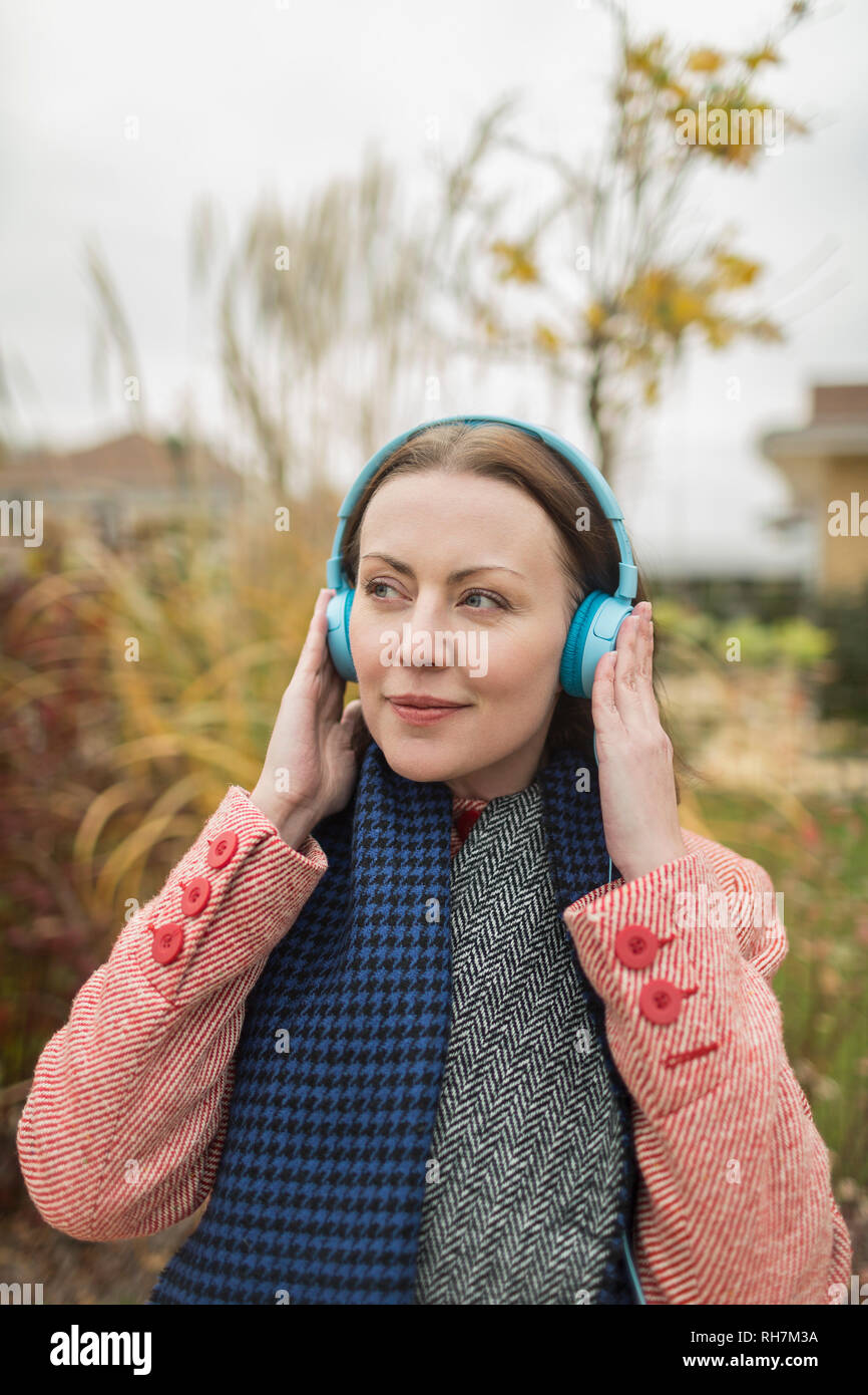 Smiling woman listening to music with headphones outside Stock Photo