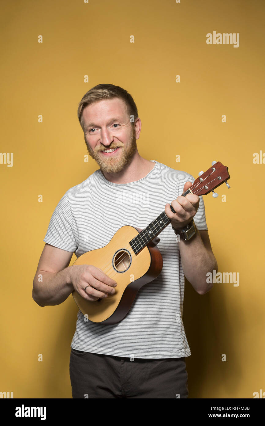 Portrait smiling man playing ukulele Stock - Alamy