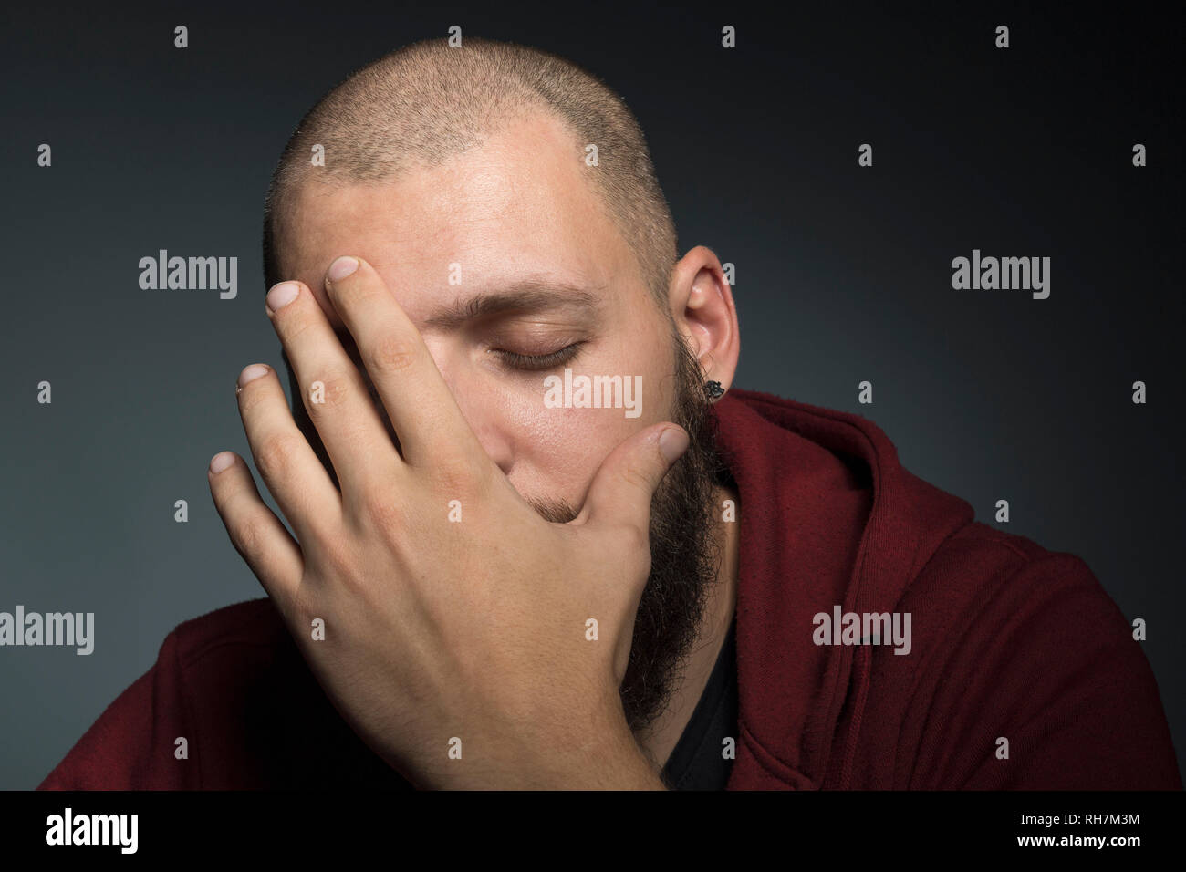 Man with eyes closed covering face with hands Stock Photo