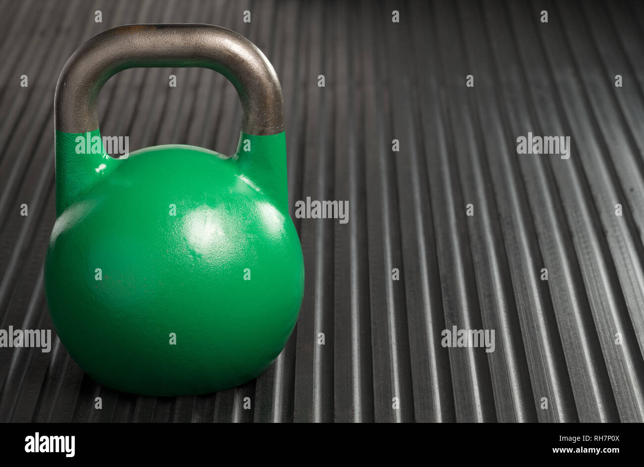 Green 24kg weight lifting kettlebell inside a gym. Copy space to the right of kettlebell. Stock Photo