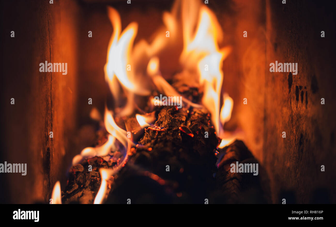 Dark pieces of wood burning in orange-yellow flame in the fire full of  ashes Stock Photo - Alamy