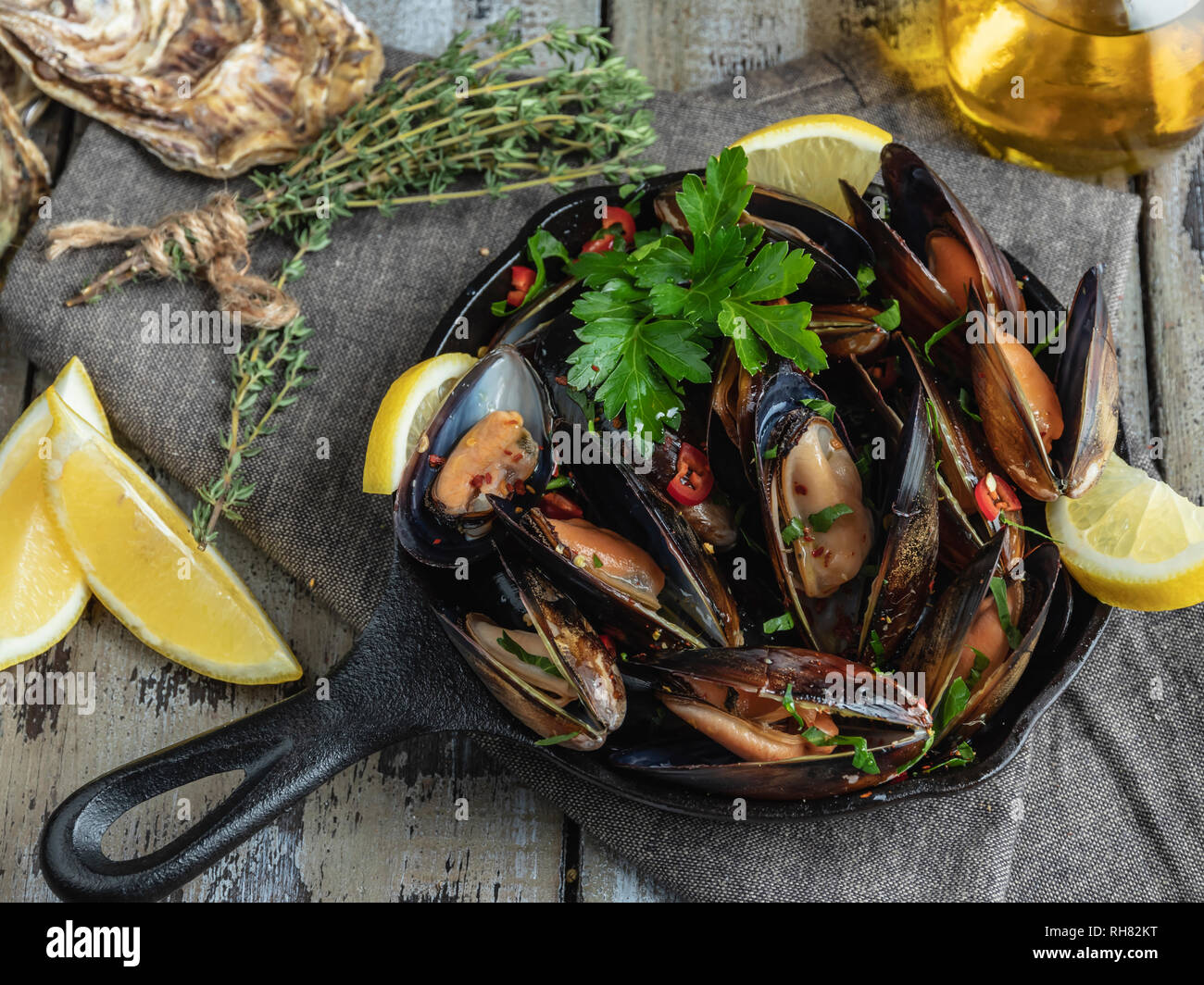 Cooked seafood clams mussels in the iron pan portion with lemon and seasoning Stock Photo