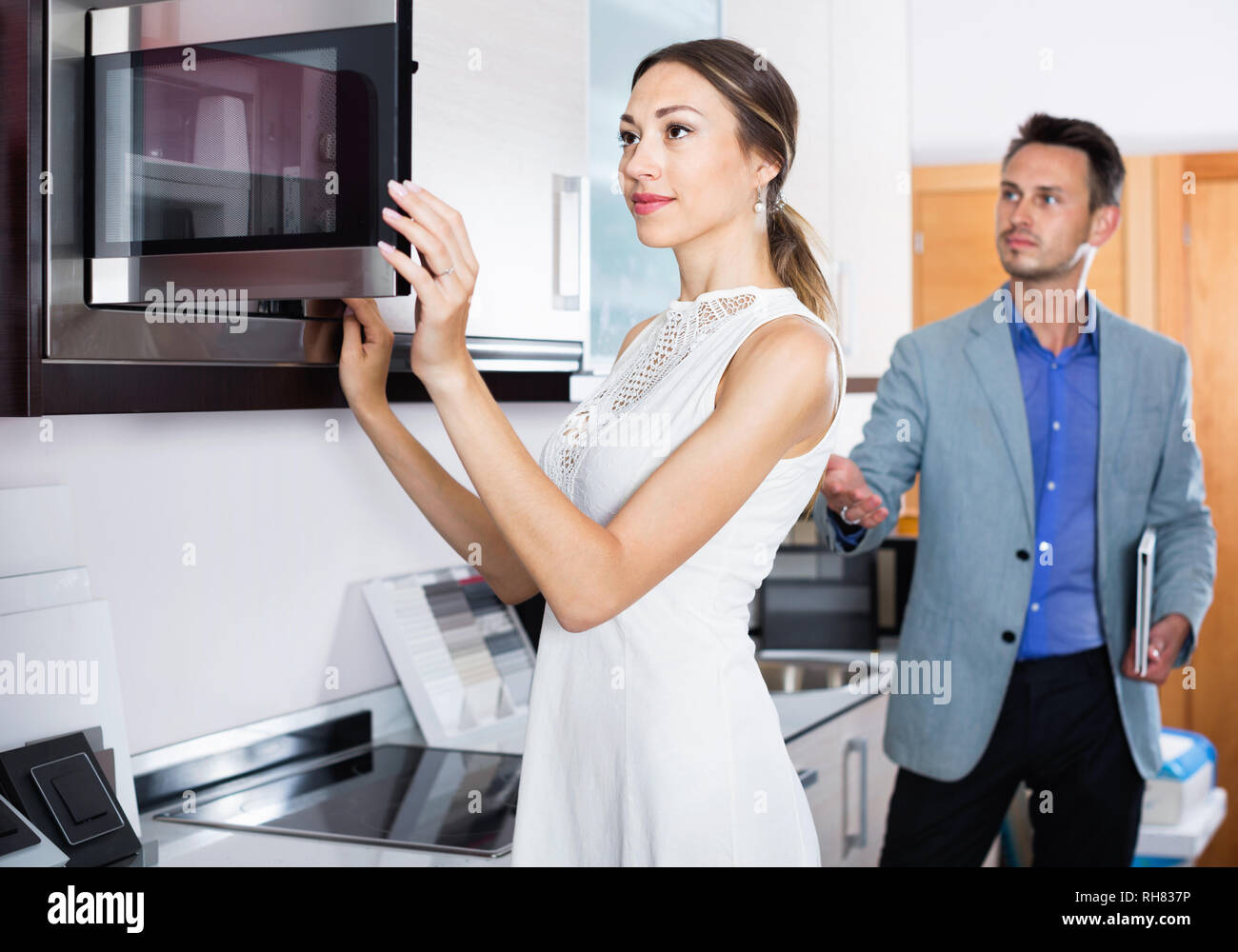 Young glad positive couple choosing microwave in household appliance section in furnishing store Stock Photo