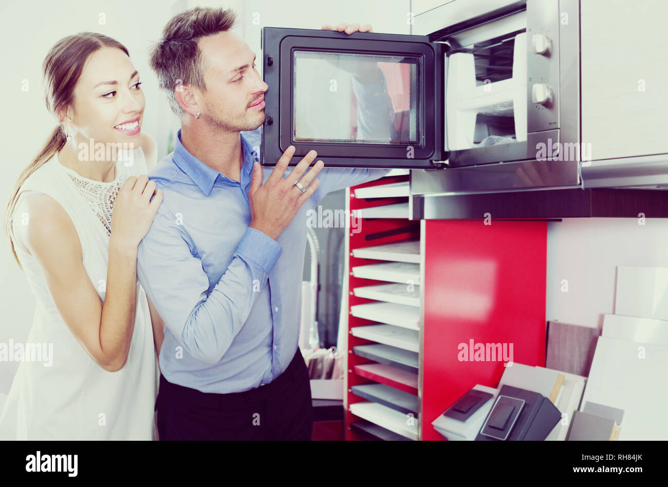 Smiling family couple looking for new modern mini oven in furniture showroom Stock Photo