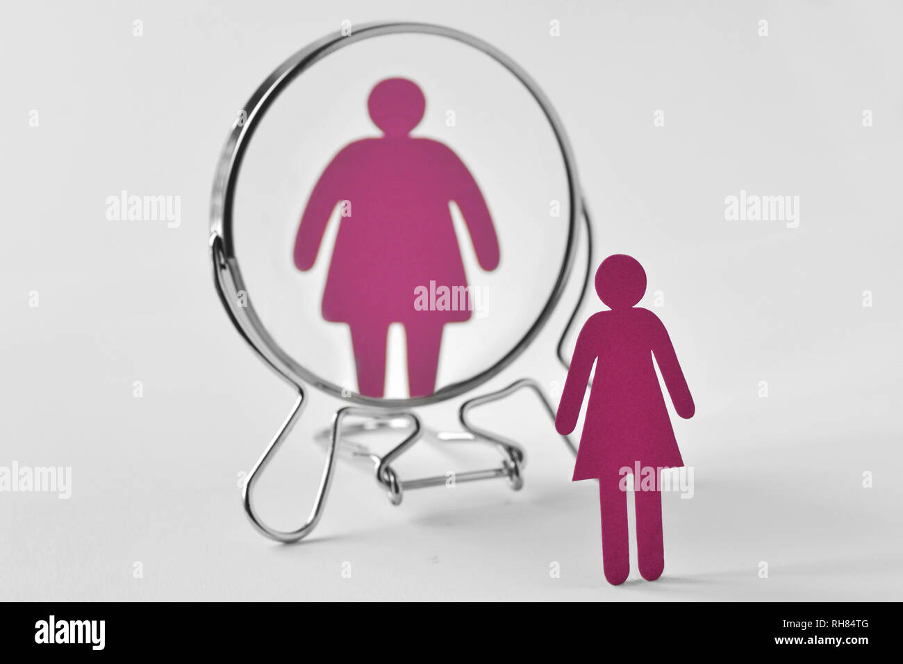 Slim paper woman looking in the mirror and seeing herself as a fat woman - Anorexia and eating disorders concept Stock Photo