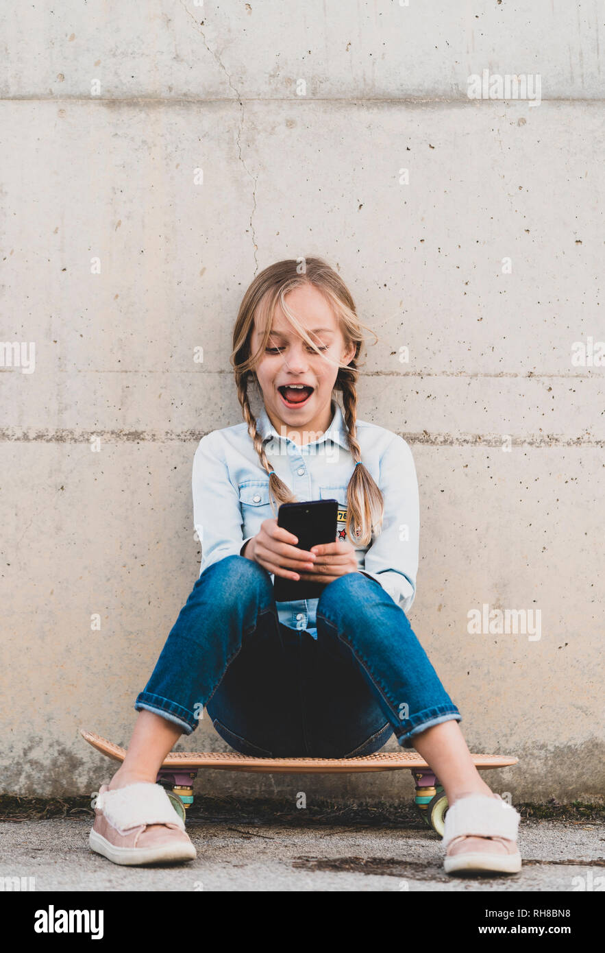 Kid using mobile phone with skate Stock Photo