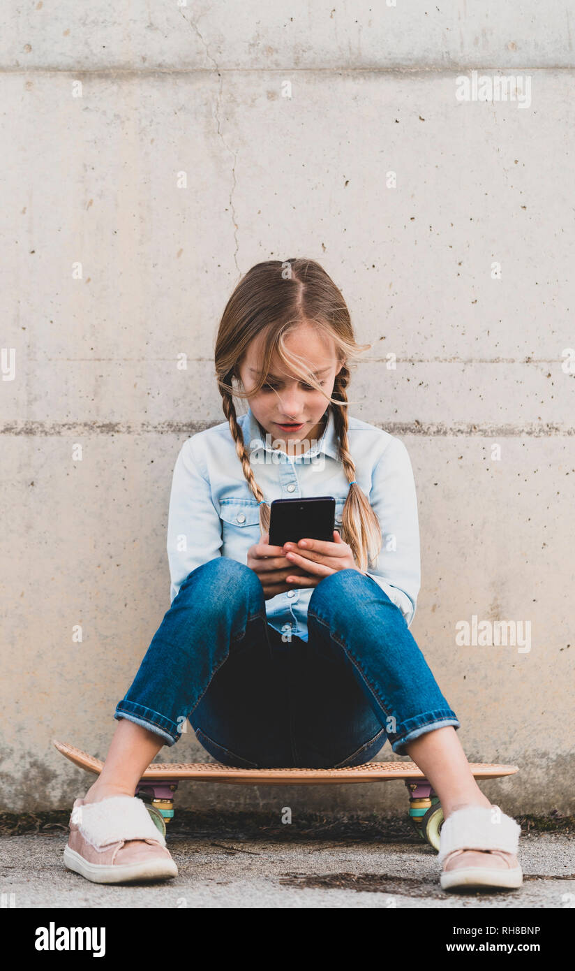 Kid using mobile phone with skate Stock Photo