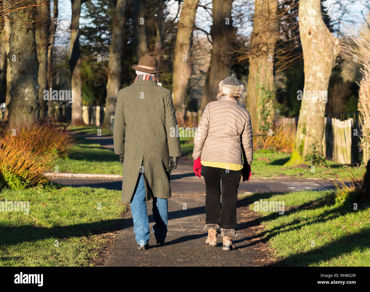 Middle aged or senior couple dressed in warm Winter clothing with scarf and hat walking together on a country path in Winter in the UK. Stock Photo