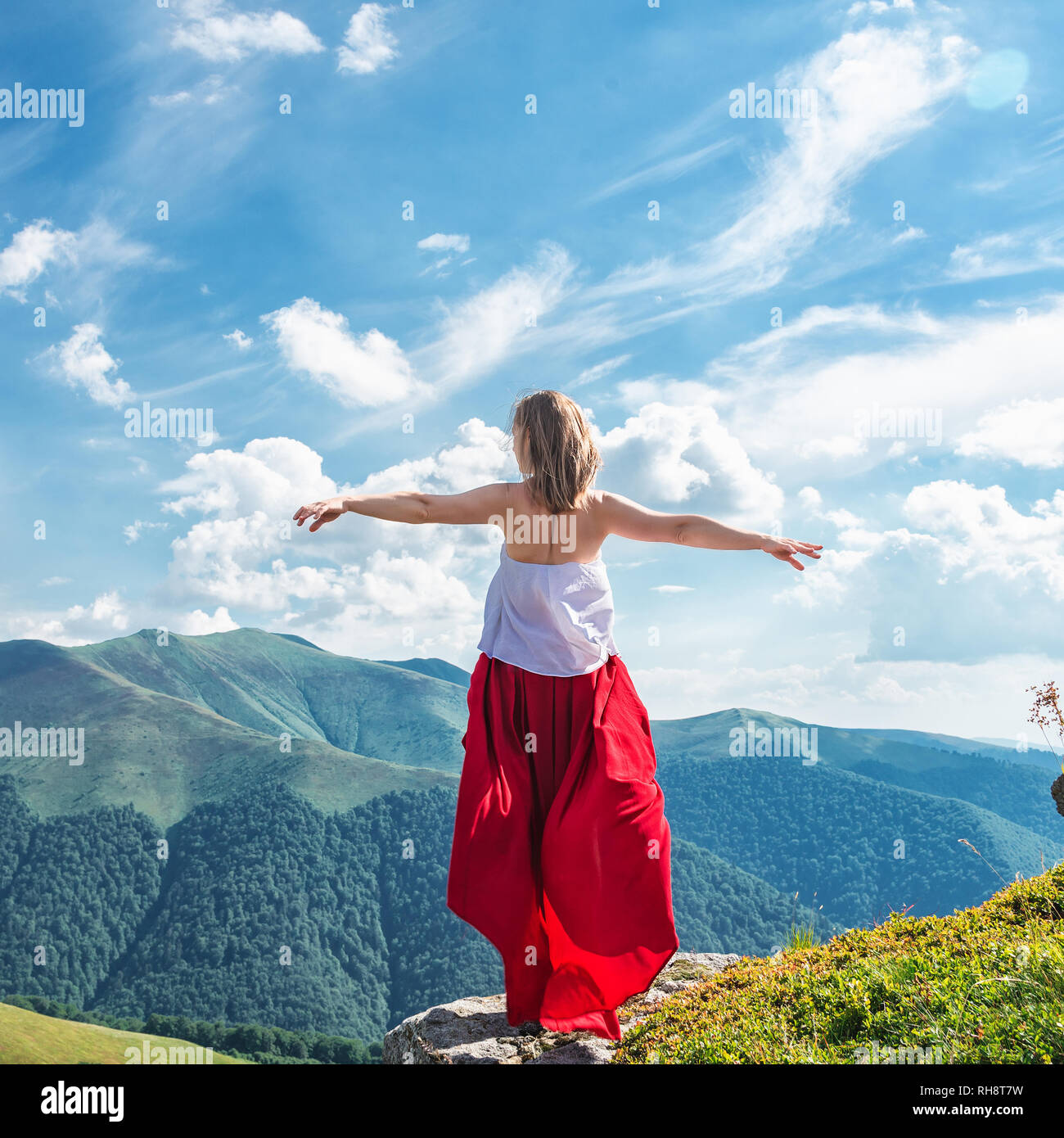 Young woman in red dress staying on the top of mountain Stock Photo - Alamy