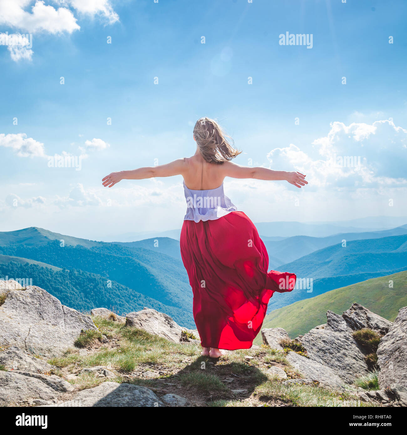 Young woman in red dress staying on the top of mountain Stock Photo - Alamy