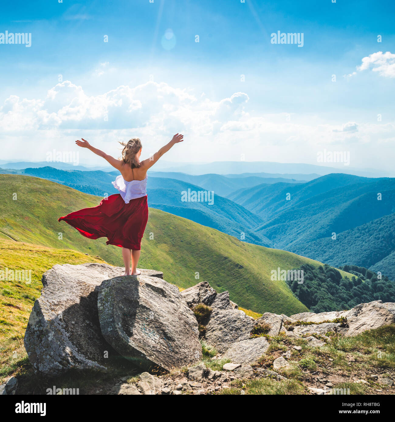 Young woman in red dress staying on the top of mountain Stock Photo - Alamy