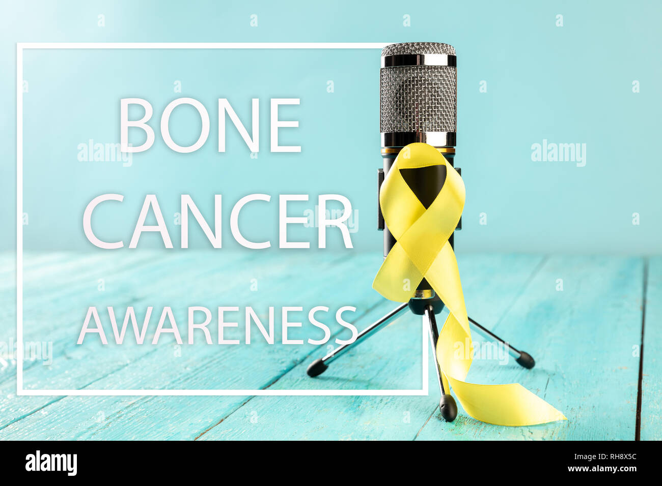Yellow ribbon symbolic color for Sarcoma Bone cancer awareness and suicide prevention on aged wood with microphone. The cancer, health, help, care, support, hope, illness, healthcare concept Stock Photo