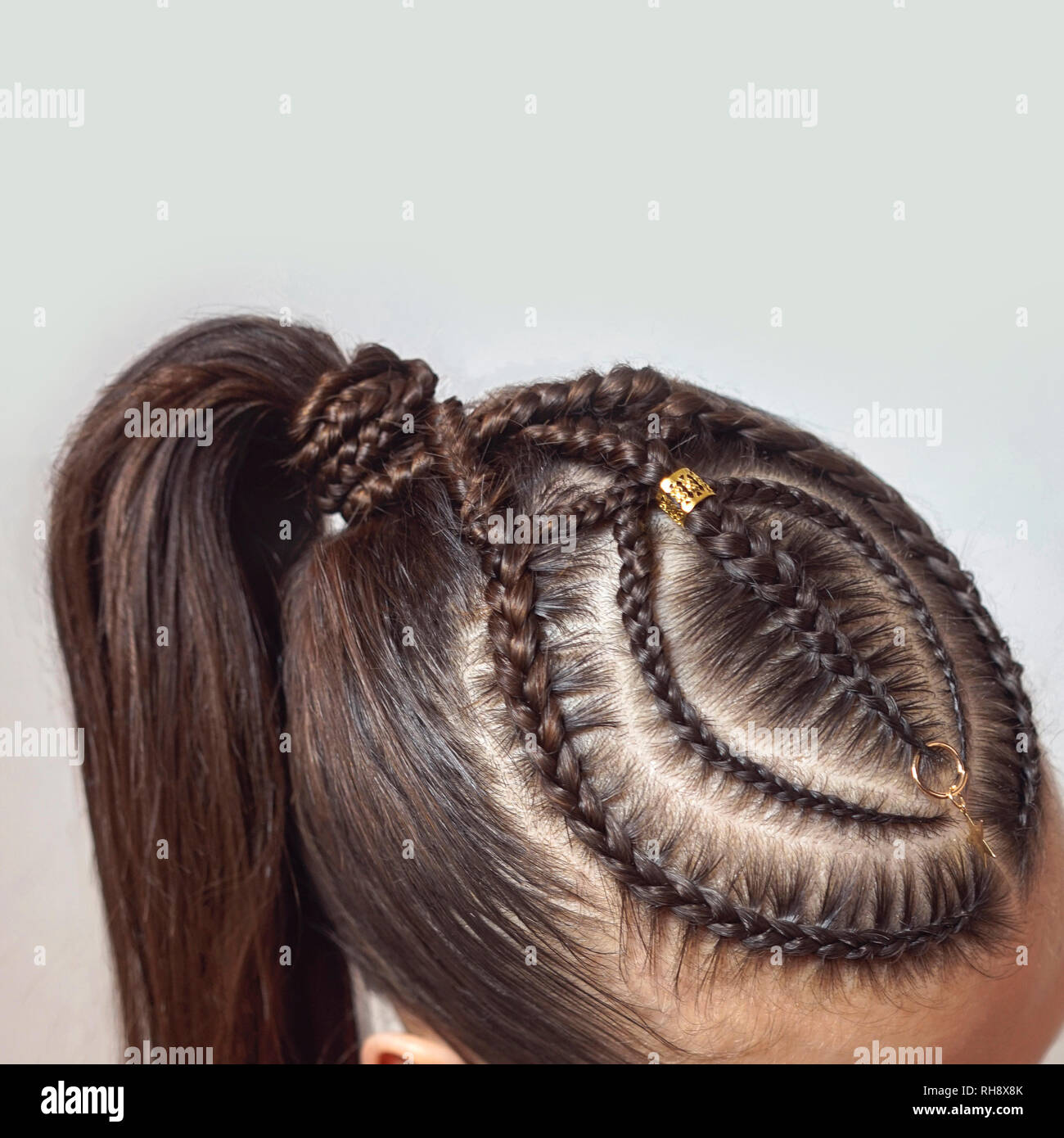 cornrows hairstyle for a girl with dark hair, thin braids tied in a tail Stock Photo