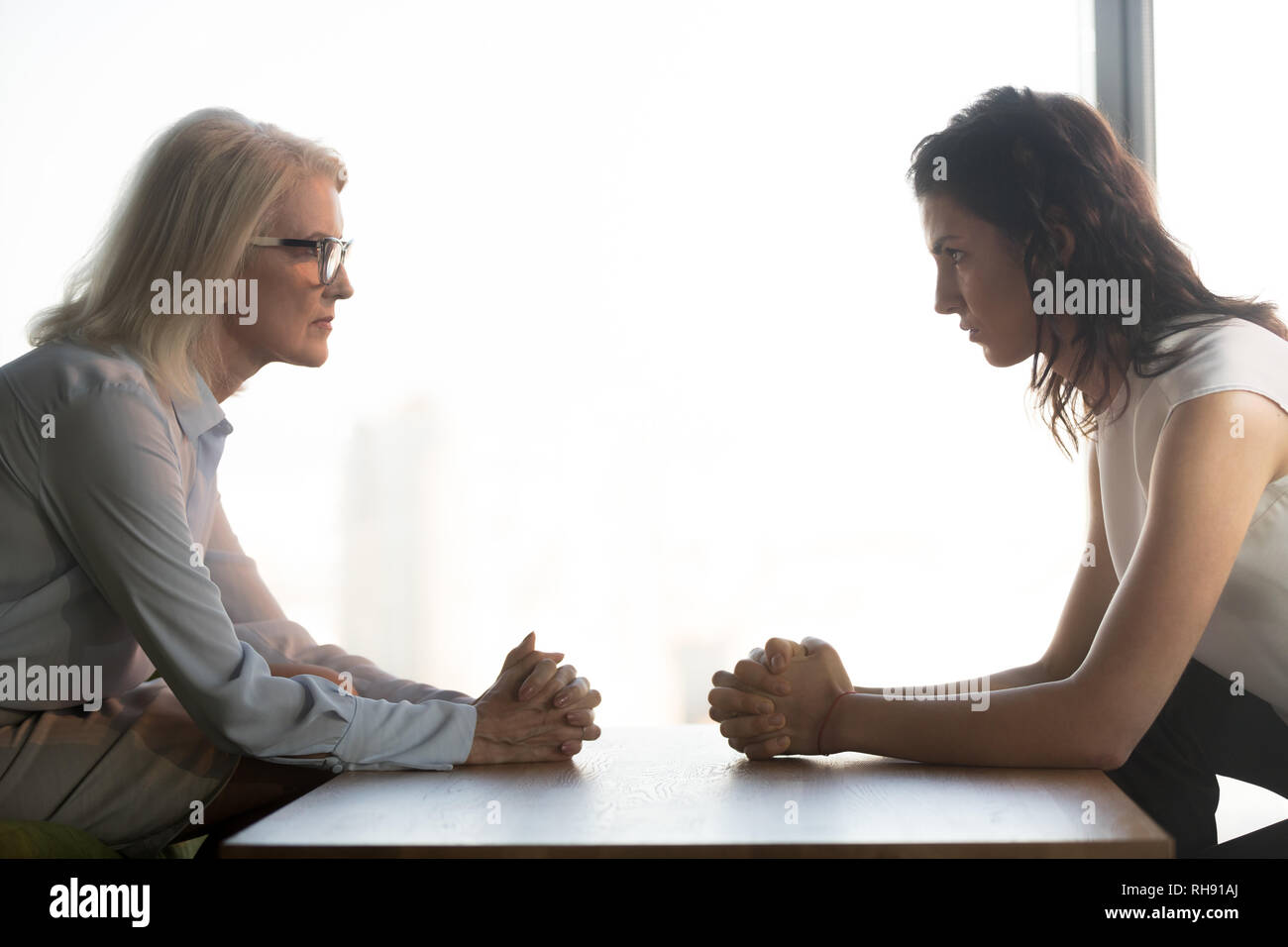 Young and old businesswomen sitting opposite, generations conflict at work Stock Photo