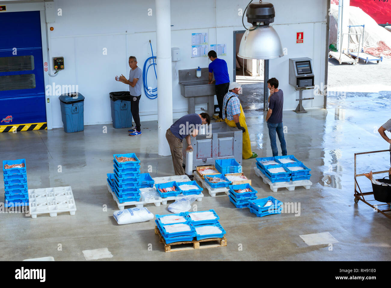 Blanes, Spain - 31 may, 2018: Buyers are traded at conveyor. Fish auction for wholesalers and restaurants. Blue plastic containers with catch of sea fish ocean delicacies. Industrial catch of fish Stock Photo