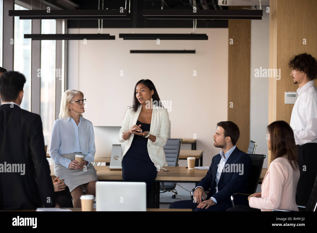 Serious asian coach speaking at diverse corporate group meeting Stock Photo