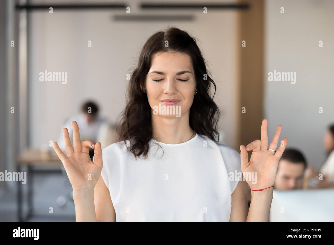 Young business woman employee meditating in office with eyes closed Stock Photo