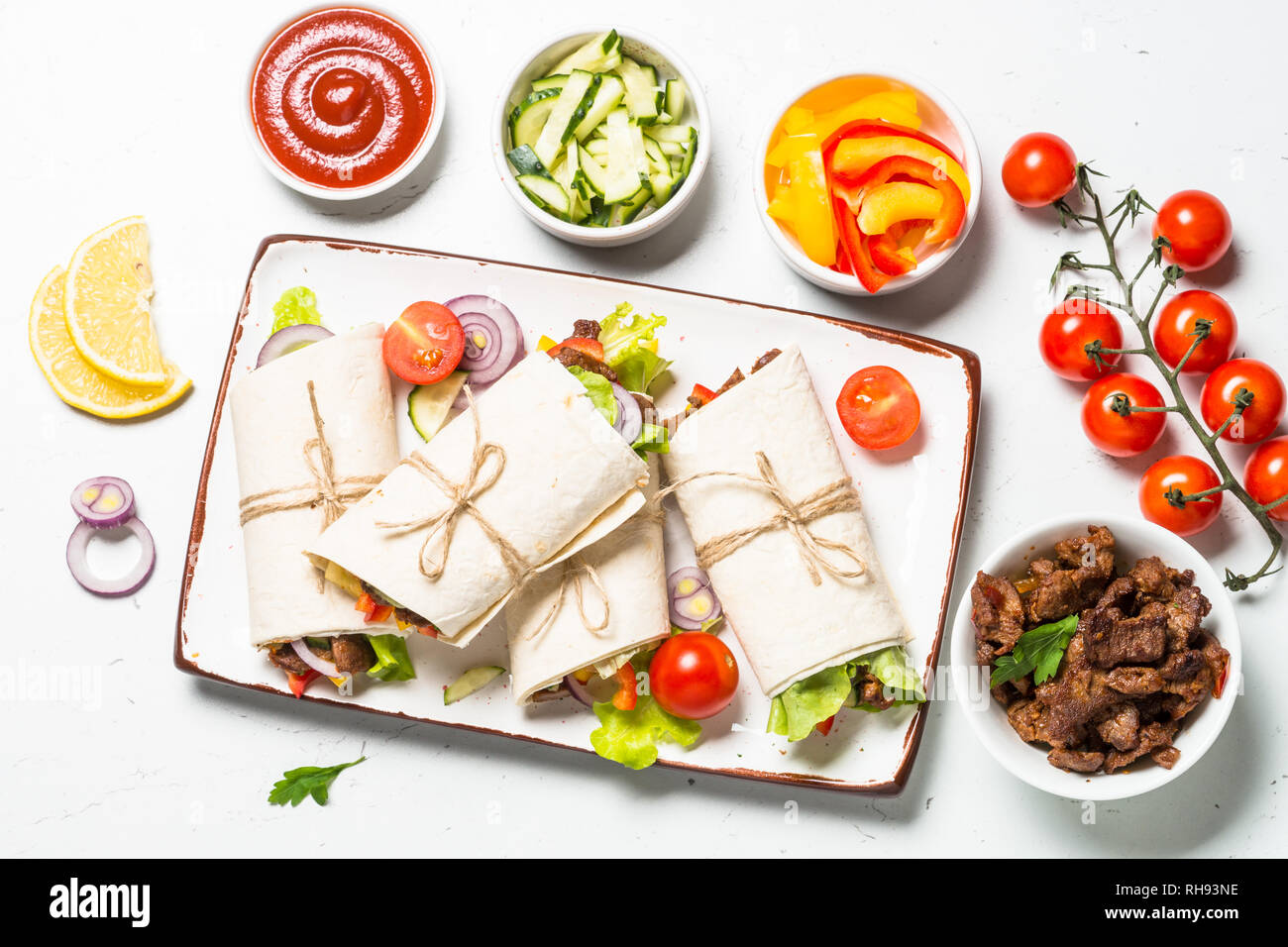 Burritos tortilla wraps with ingredients beef and vegetables on white