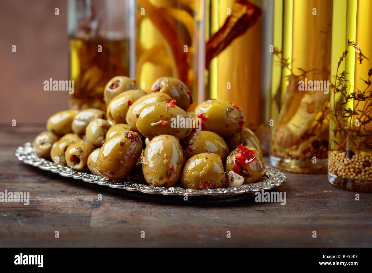 Spiced green olives and bottles with olive oil on a wooden table Stock ...