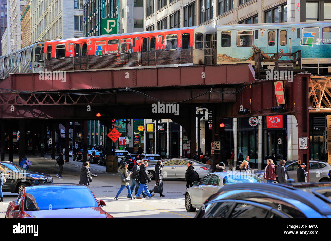 L train running on elevated train tracks with street traffics