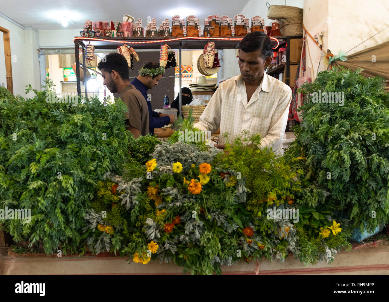 Flower vendors preparing floral garlands and crowns on a market, Asir province, Muhayil, Saudi Arabia Stock Photo