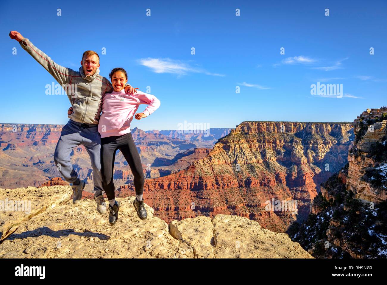 Mather Point Rim Trail Pair, jumping, in front of the gigantic gorge of the Grand Canyon, view ...