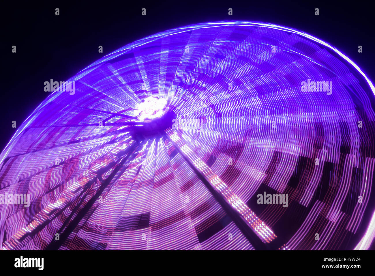 Ferris wheel in motion at the amusement park, night illumination. Long