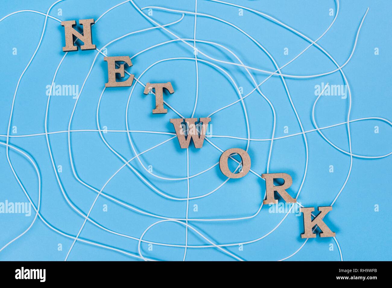 The word network with wooden letters in the form of an abstract spider web, blue background. Stock Photo