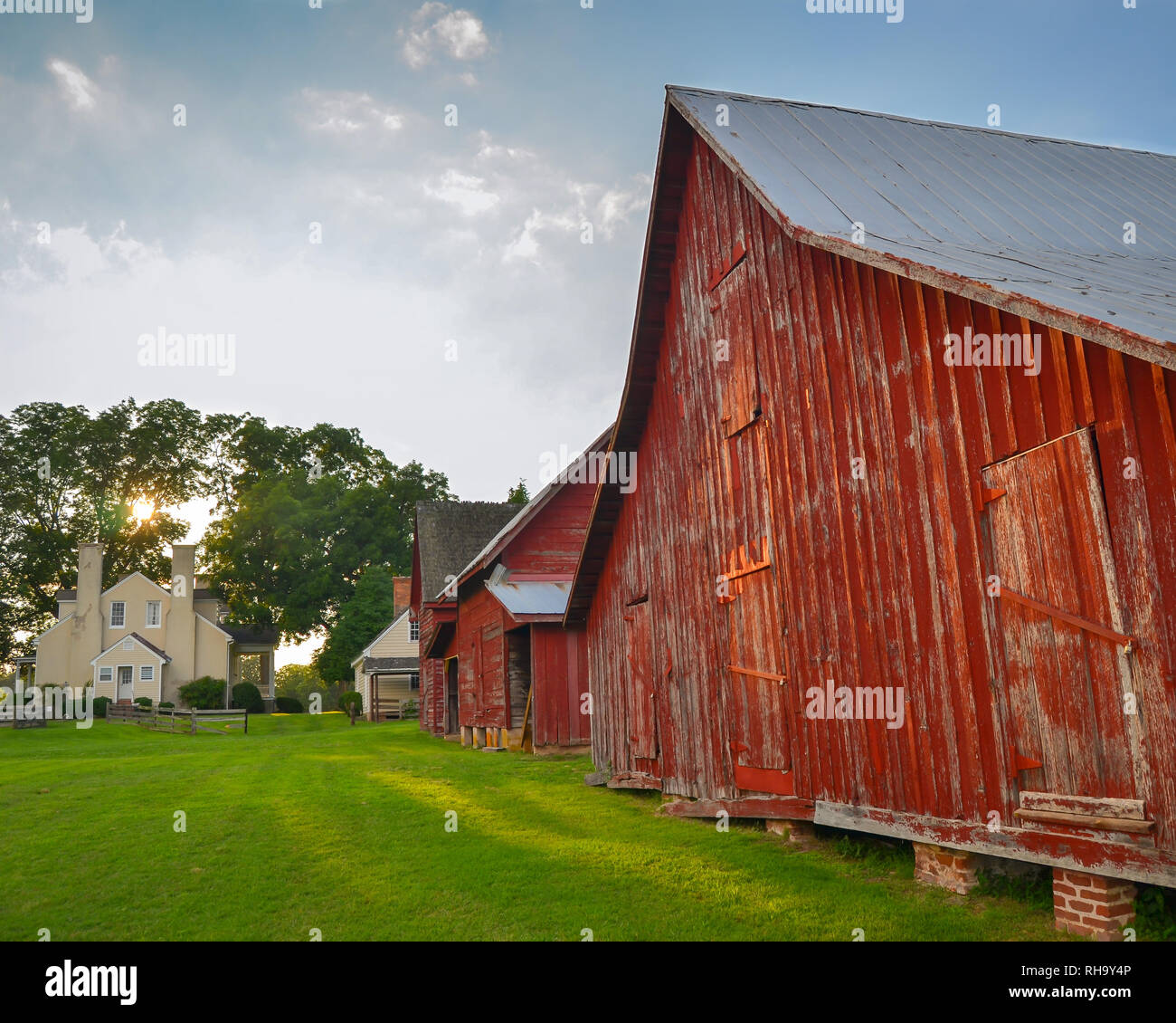 Historic Old Red Barns And A House In Afternoon Sunlight At